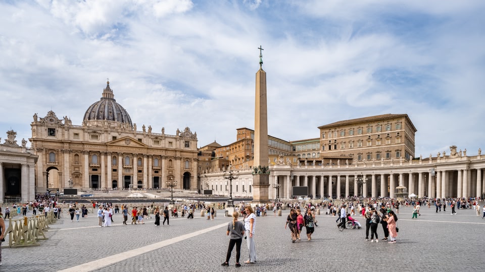 St. Peter's Basilica in Rome with a large crowd of tourists visiting the area.
