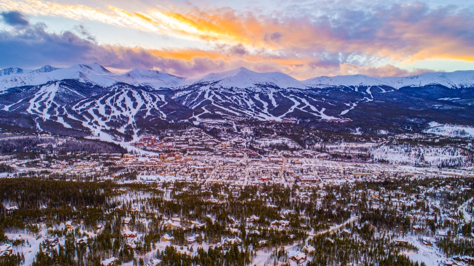 A snowy street in Breckenridge, Colorado, with people walking and shops decorated with lights.