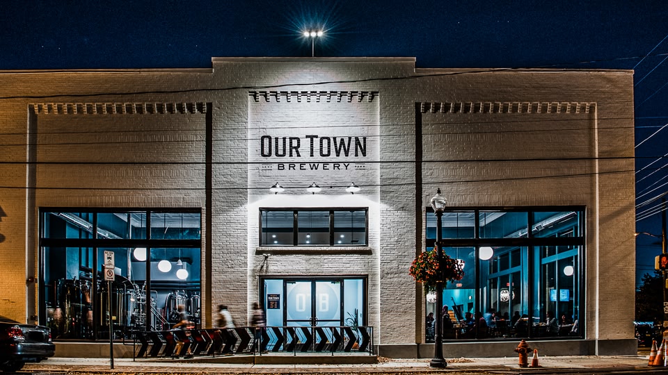 Exterior of Our Town Brewery at night with people inside.