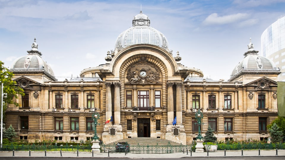 Facade of a grand, old building with intricate architecture and domes in Bucharest, Romania.