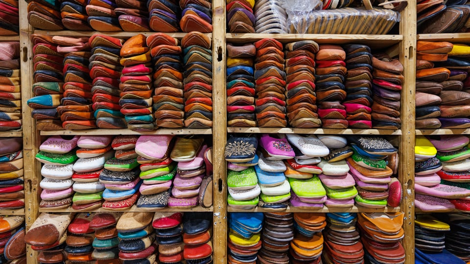 Rows of bright leather slippers stacked on wooden shelves in a market in Fes.