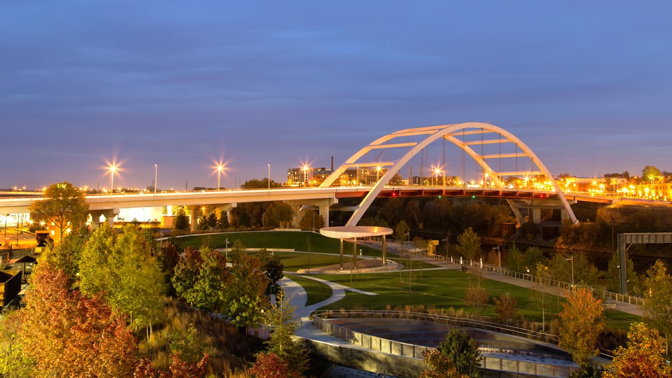 A nighttime view of a bridge with city lights and a park below