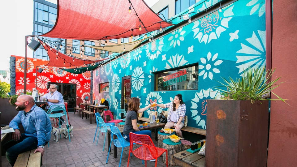 Outdoor seating area of a bar with colorful chairs and people socializing