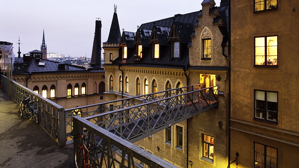 A nighttime view of Stockholm city with illuminated buildings and a bridge connecting them.