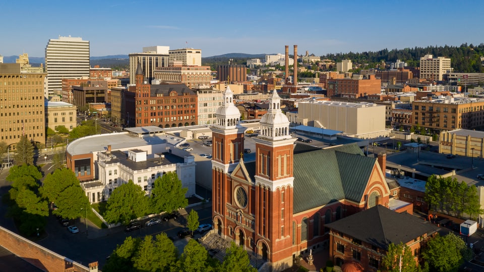 Aerial view of Spokane city center with various buildings and a prominent historic church.