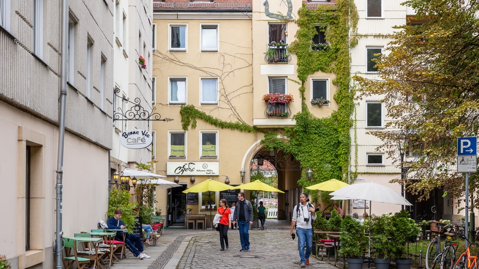 A street scene in Berlin with people walking and cafes on the side.