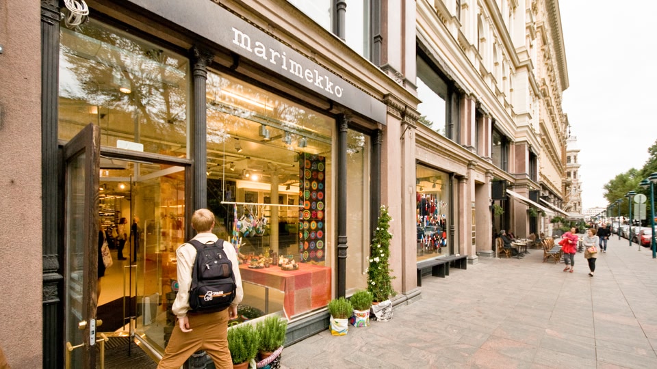 A person walking past a store front on a busy street.