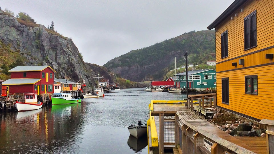 A scenic river view with colorful houses and boats docked along the riverbank in Saint John, New Brunswick, Canada.