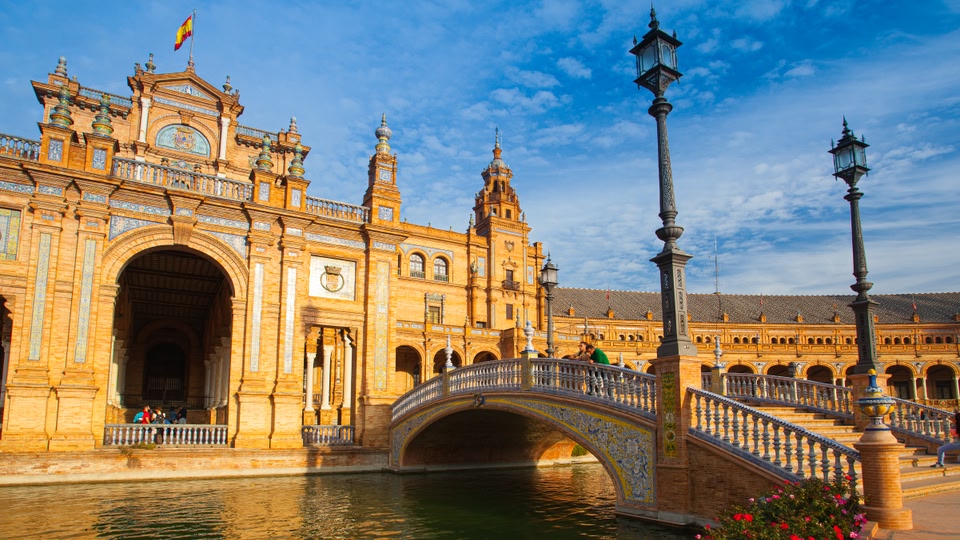 A grand, ornate building with a bridge in front and a body of water reflecting the structure.
