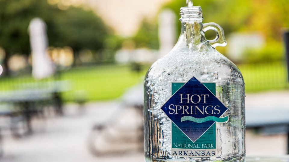 A glass bottle of Hot Springs National Park water with condensation on the outside, indicating it is cold.