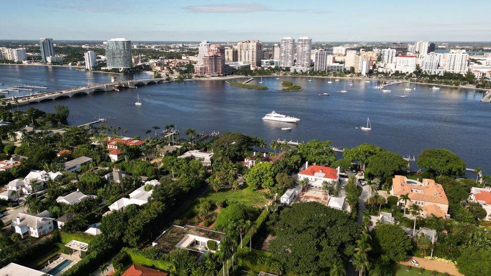 Aerial view of a waterfront city landscape showing buildings, a bridge, and a marina with boats.