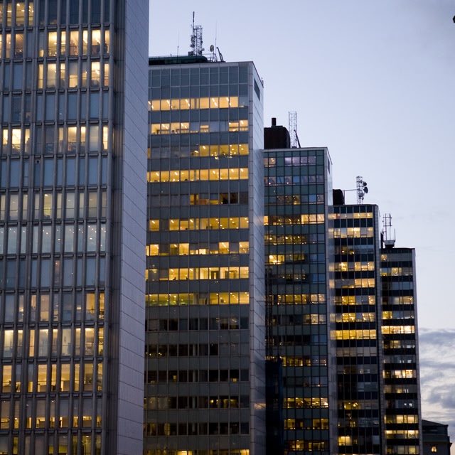 A group of modern office buildings with illuminated windows at dusk in Stockholm, Sweden.