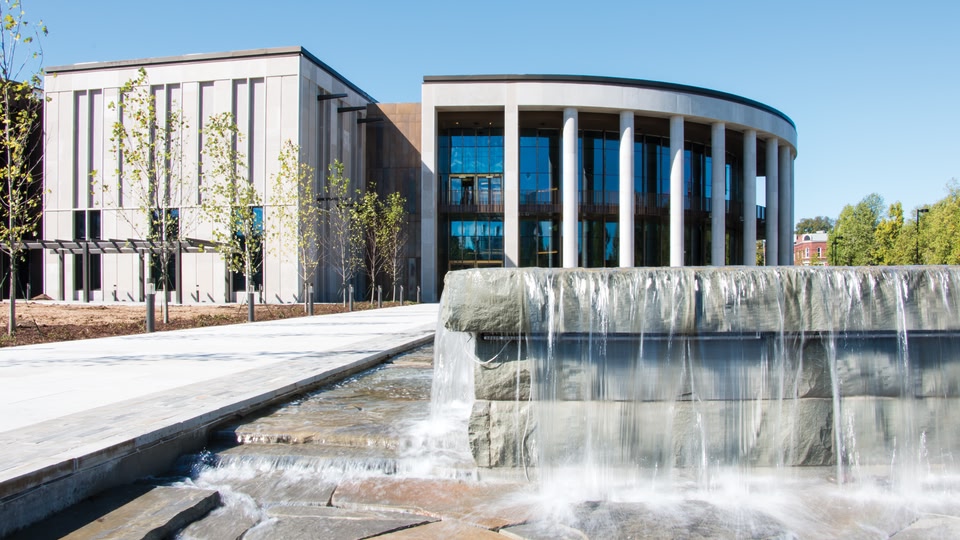 A modern building with a flowing water feature in front of it.