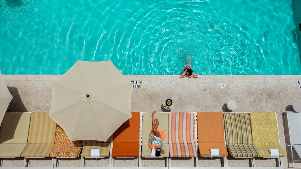 Aerial view of a beach with white sand, turquoise waters, and modern buildings along the shoreline in Sarasota, Florida.