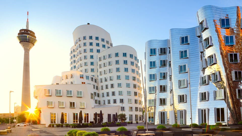 Modern architectural buildings with the sun setting or rising in the background.